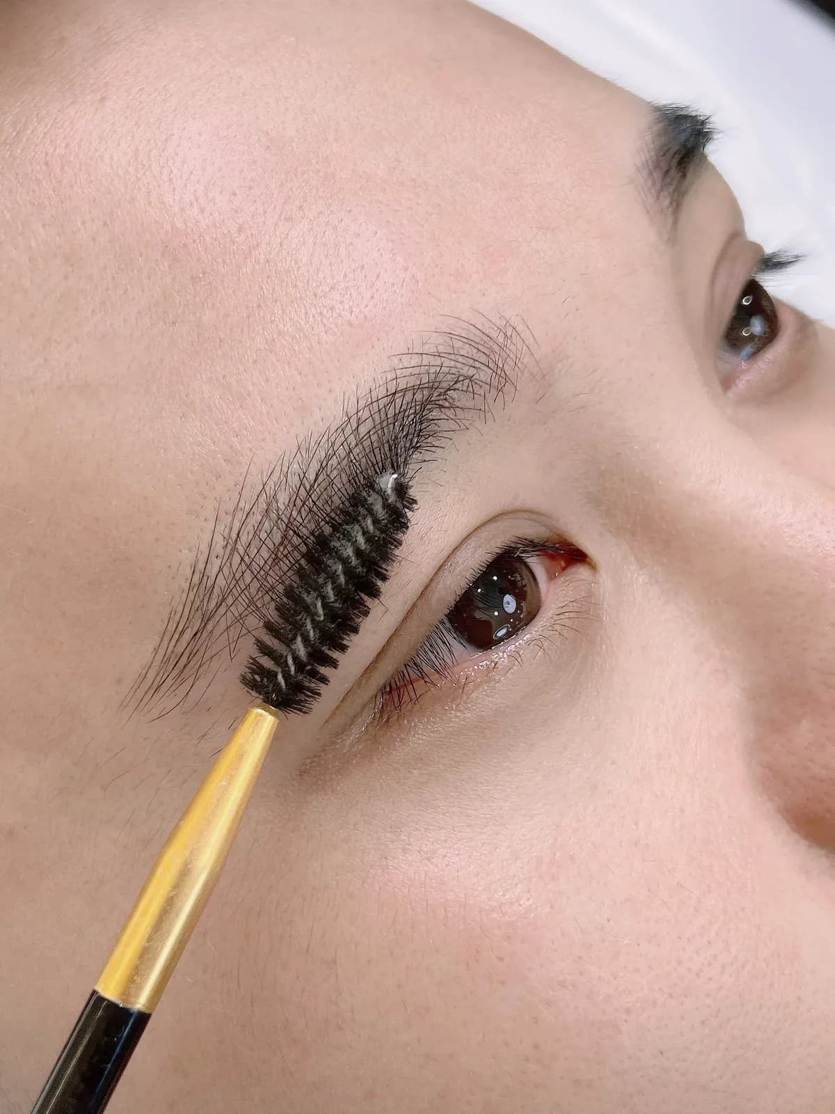 Brushing through freshly finished brows